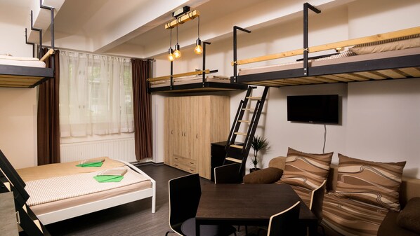 A compact room with bunk beds, a desk, a chair, and a couch.