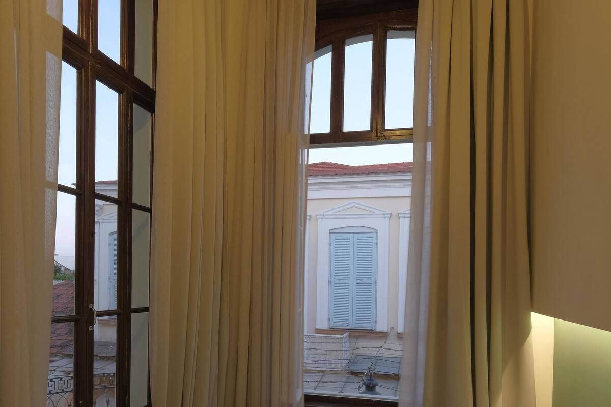 A bedroom with a bed, curtains, and a window with a view of a building.