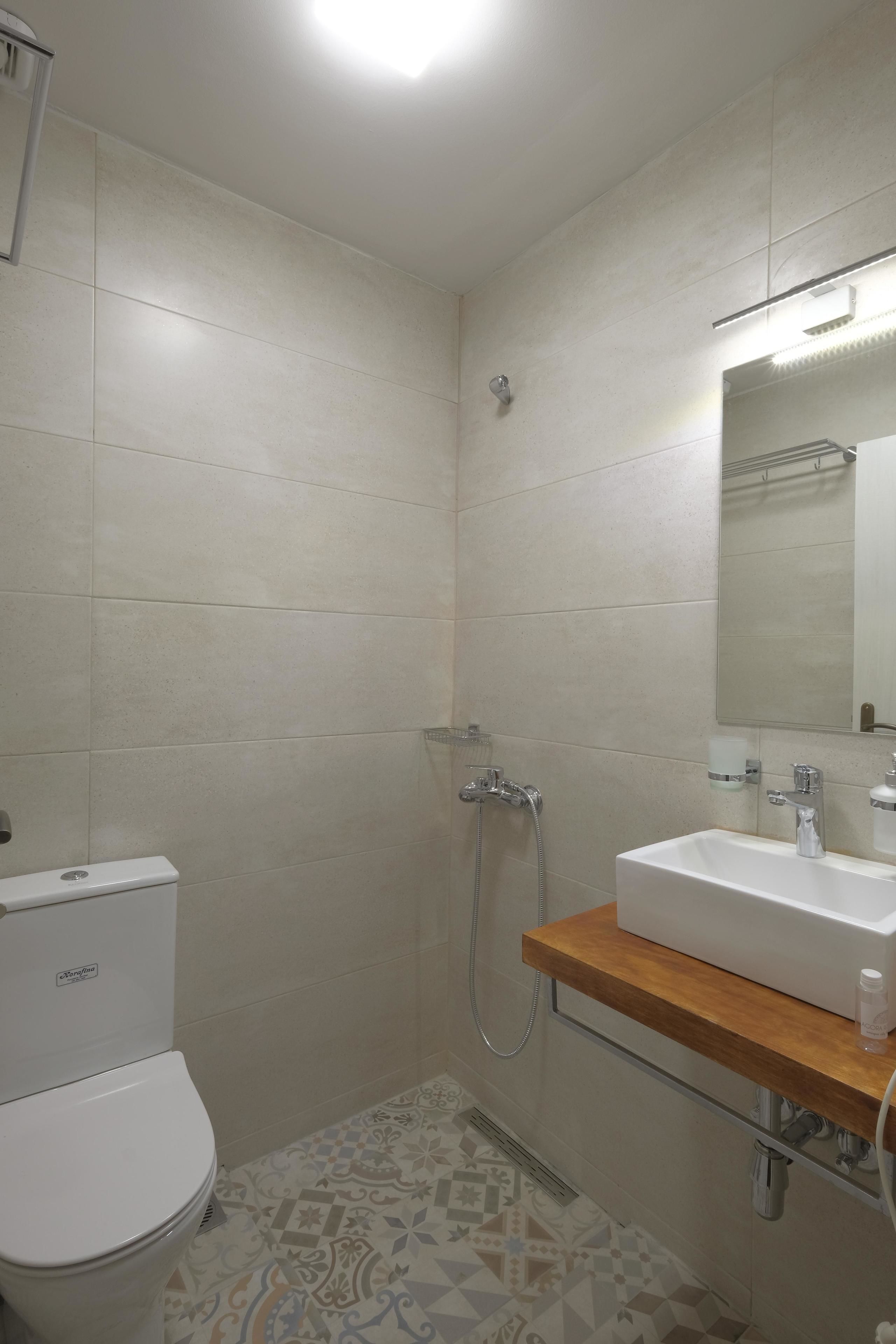 A bathroom with a toilet, shower, and sink.