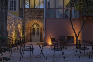 Un espacio de estar al aire libre con paredes de piedra, una puerta de madera y un árbol pequeño.