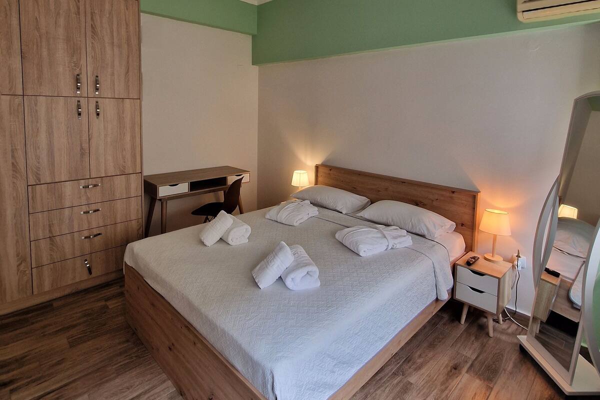 A neatly arranged bedroom with a wooden bed, a desk, and a wardrobe.