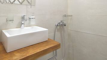 Un baño moderno con lavamanos, espejo y ducha blancos.