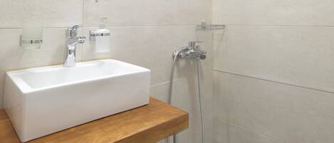 Un baño moderno con lavamanos, espejo y ducha blancos.