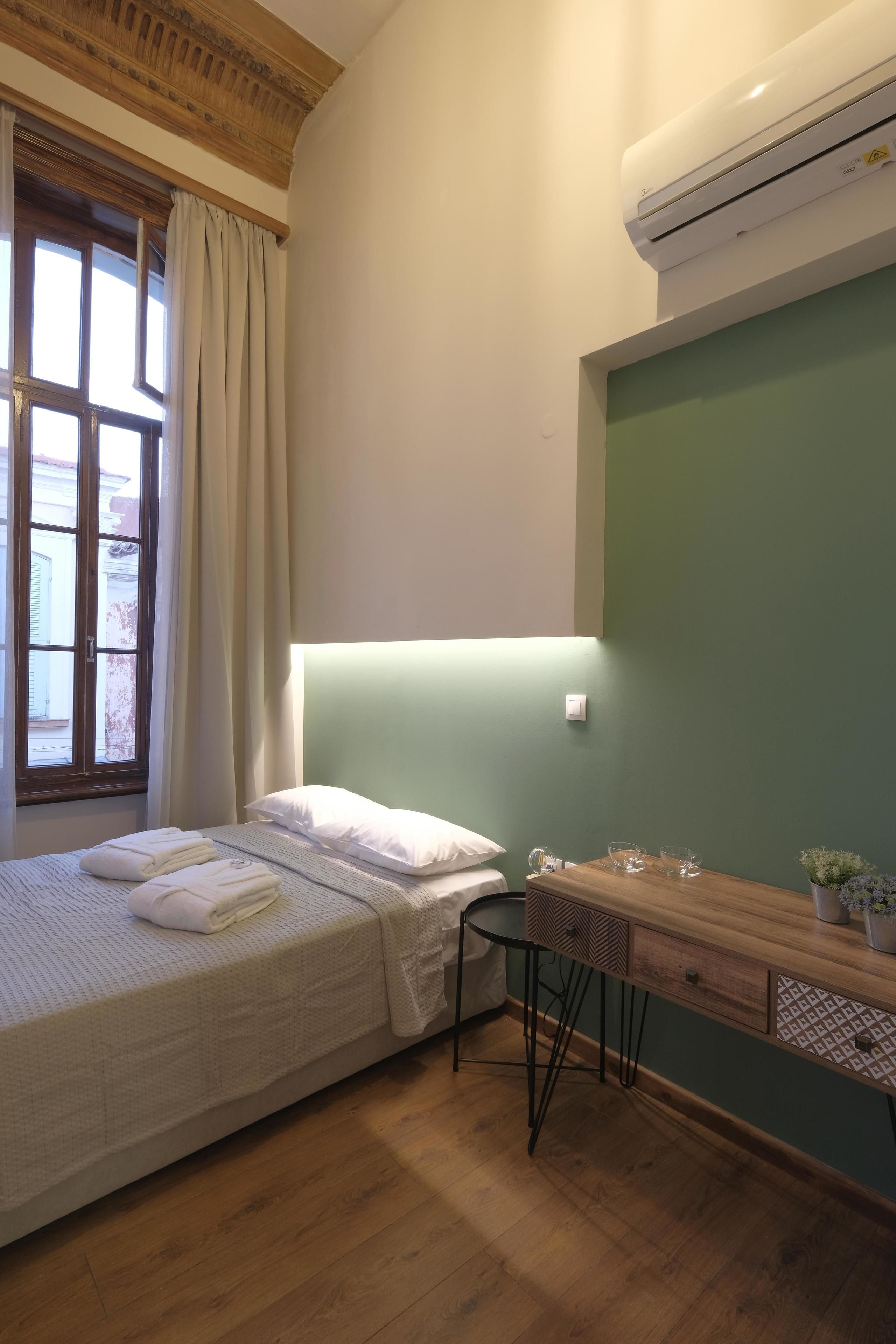 A bedroom with a bed, bedside table, and a window with curtains.