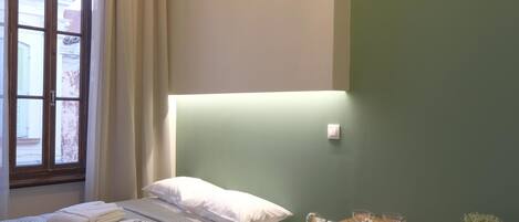 A bedroom with a bed, bedside table, and a window with curtains.