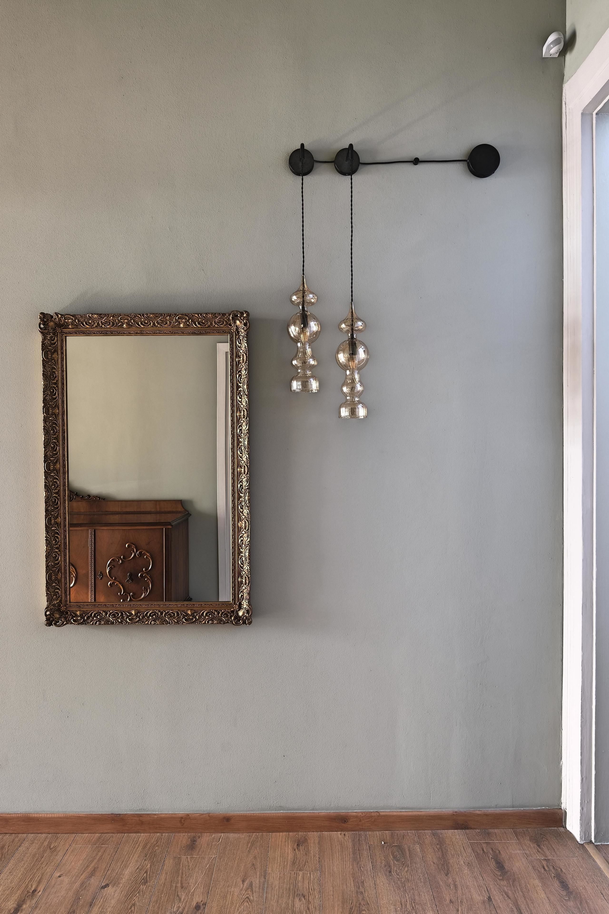 Une pièce dotée d’un grand miroir décoratif, d’une commode en bois et d’un luminaire fixé au mur.