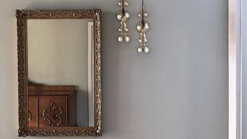Une pièce dotée d’un grand miroir décoratif, d’une commode en bois et d’un luminaire fixé au mur.