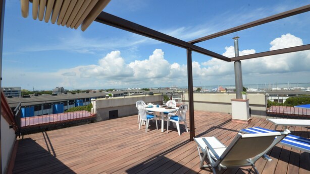 A wooden deck with a table and chairs, overlooking a marina with boats. - Residence Porta del Mare (Lignano Sabbiadoro)