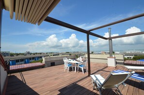 Eine Holzterrasse mit Tisch und Stühlen mit Blick auf einen Jachthafen und Boote.