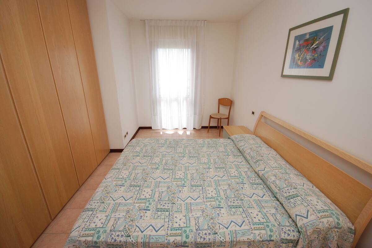 Ein Schlafzimmer mit einem Bett, einem Sessel, einem Kleiderschrank und einem Bild an der Wand.
