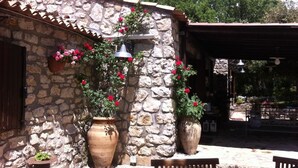 A stone building with a tiled roof, potted plants, and a wooden bench. - Villa Misita (Prizzi)