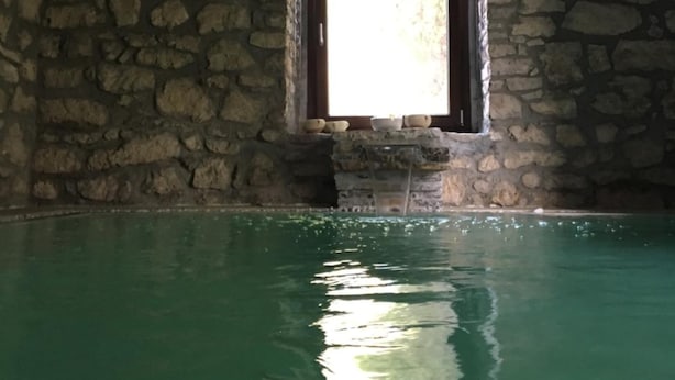 A stone-walled room with a small window and a pool. - Villa Misita (Prizzi)