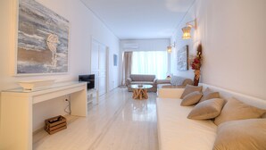 A modern living room with a glass-top coffee table, a sofa, a television, and a painting on the wall. - L' apartment blanc dans le centre de Glyfada (Glyfada)