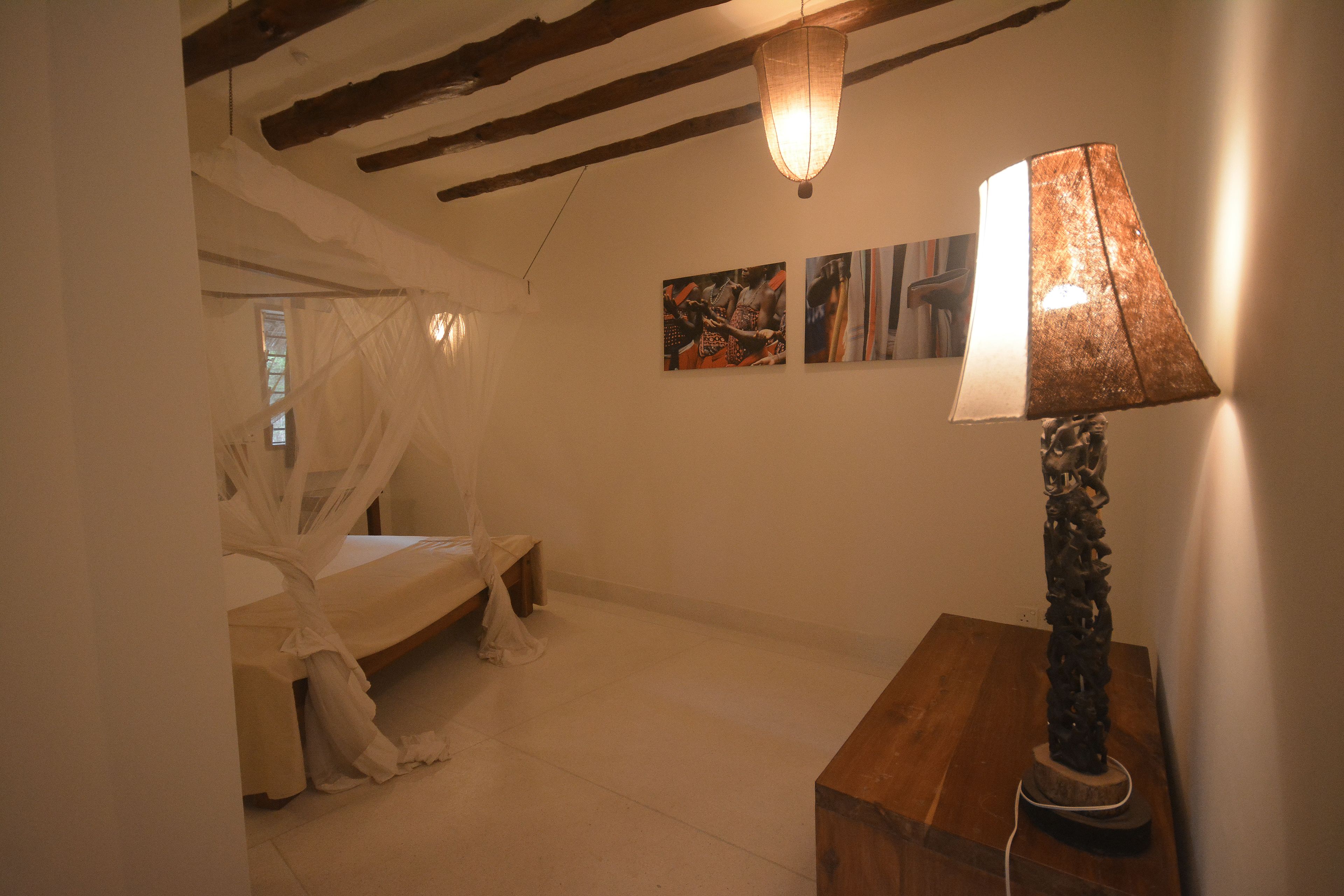 Un dormitorio con cama a dosel, una mesita de noche de madera y cuadros en la pared.