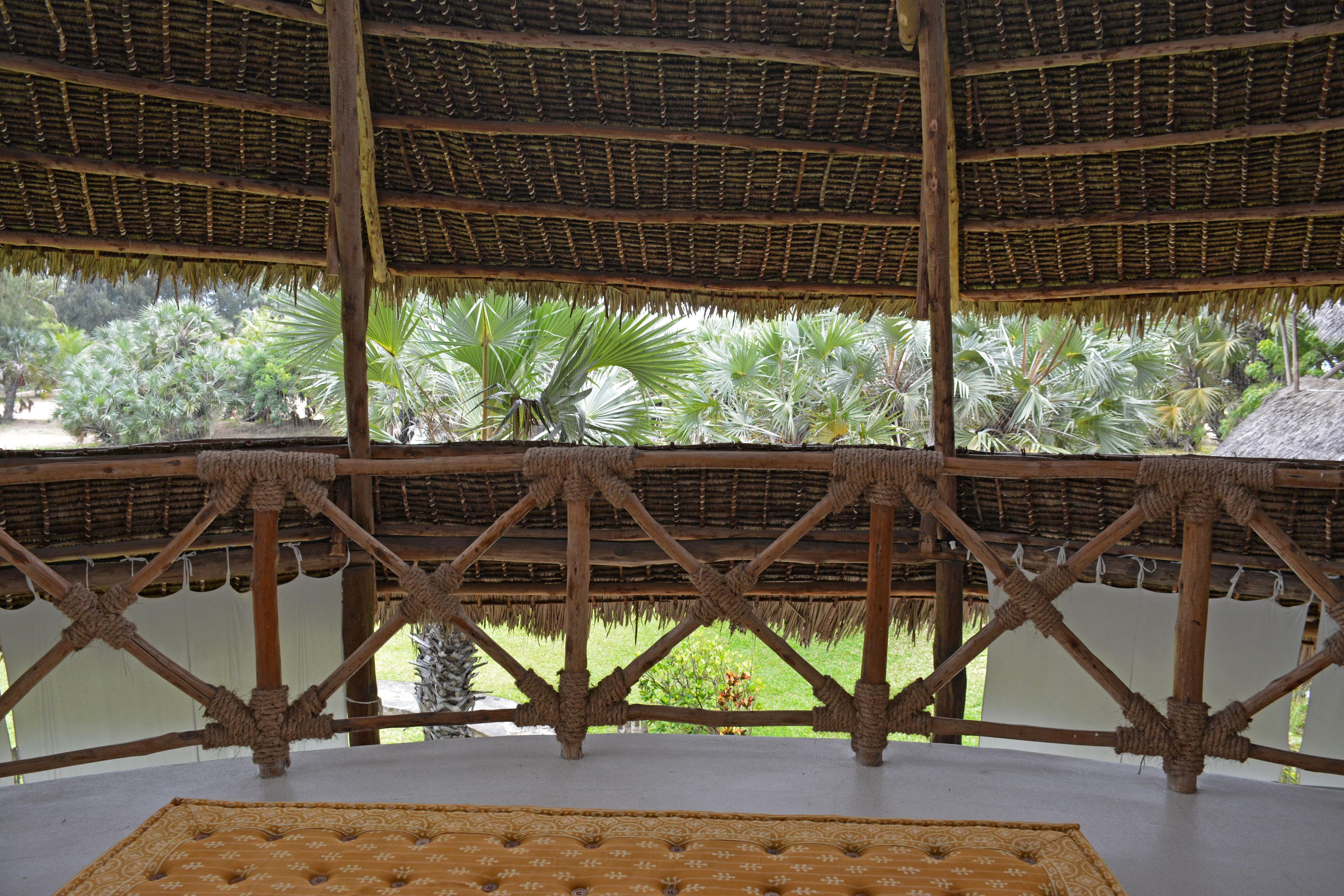 A thatched-roof structure with a view of palm trees.