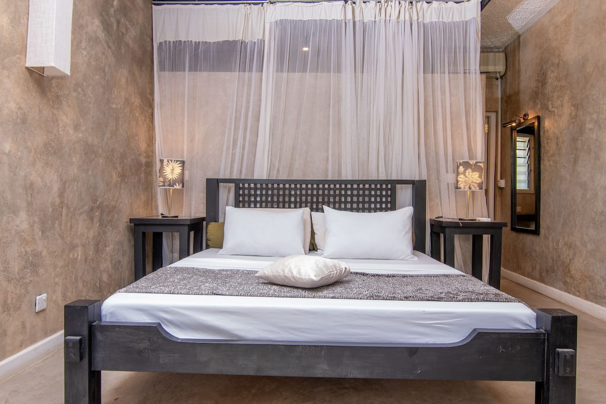 Ein Bett mit Baldachin, zwei Nachttische und ein Spiegel an der Wand.