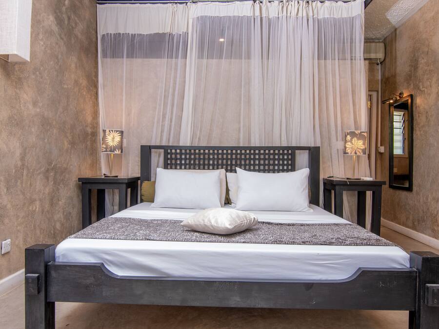 Ein Bett mit Baldachin, zwei Nachttische und ein Spiegel an der Wand.