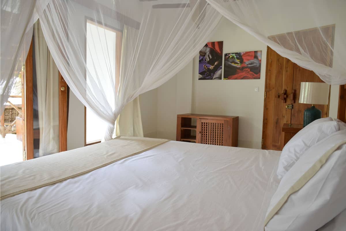 Ein Schlafzimmer mit einem Bett, einem Holzschrank, einer Wandleuchte und Kunstwerken.