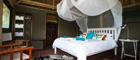 A bedroom with a canopy bed, wooden furniture, a cowhide rug, and a small bedside table.