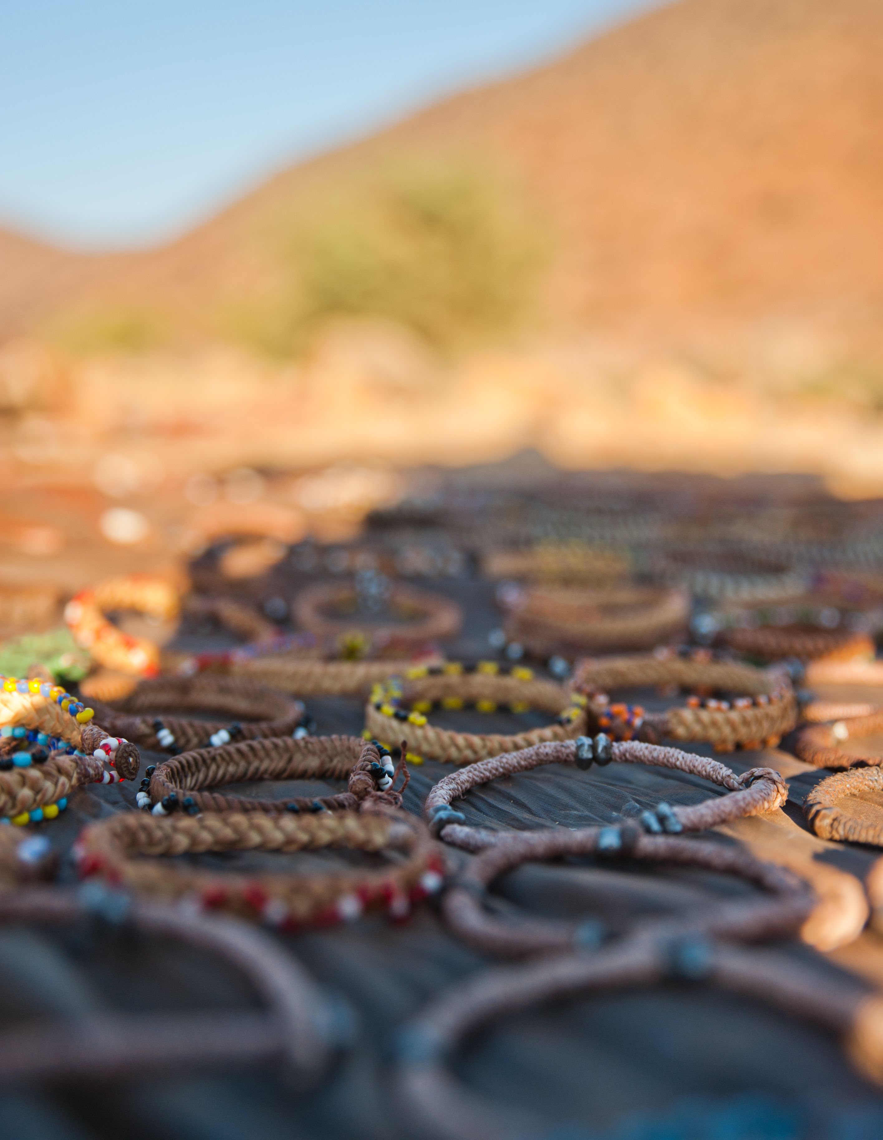 A variety of woven bracelets with beads on a wooden surface.