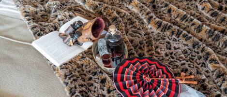 A leopard print blanket, a book, a pair of glasses, a bottle, and a patterned umbrella on a couch.