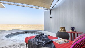 Zona exterior moderna amb banyera d'hidromassatge, taula amb un ram i vista al desert.
