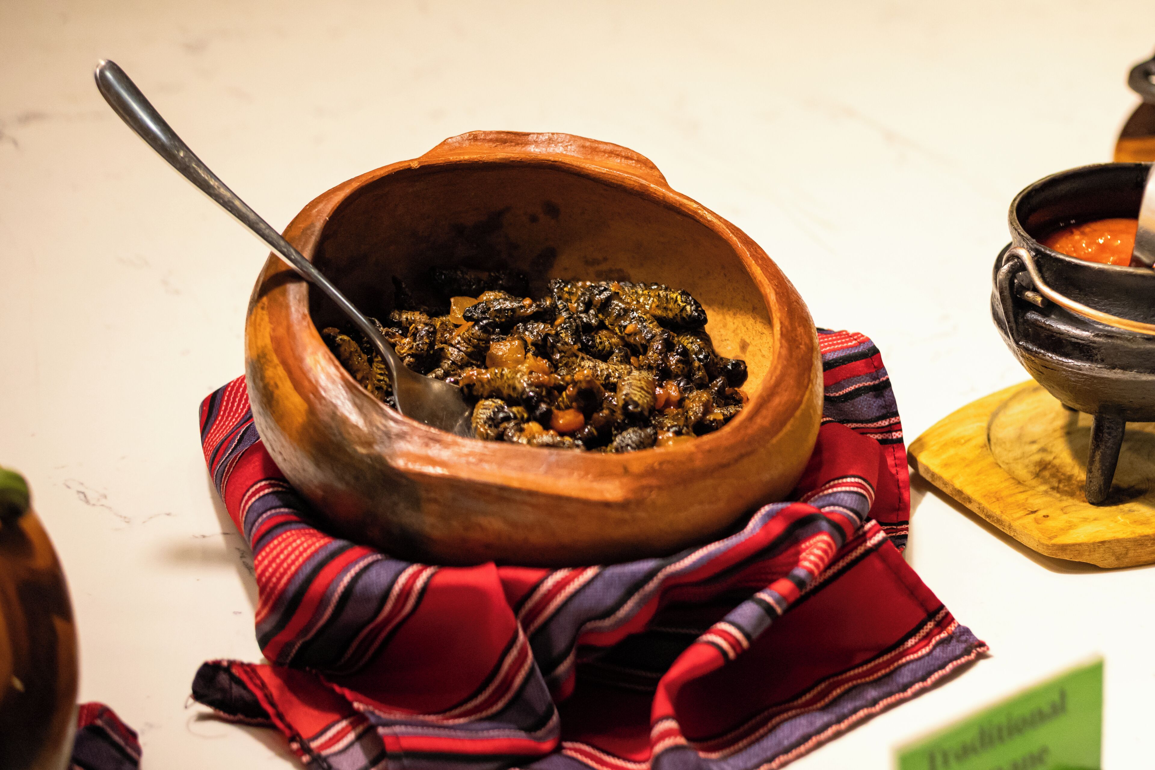 Una olla de barro tradicional con una cuchara, sobre un paño a rayas.