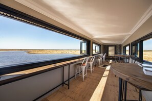 A modern interior with a view of the beach, wooden flooring, and bar seating. - Etosha King Nehale (Omuthiya)