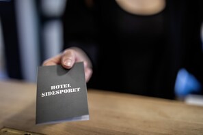 A hand holding a booklet titled "HOTEL SIDESPORET."