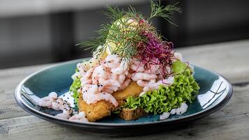 Un plato de comida con camarones, lechuga y una guarnición encima.