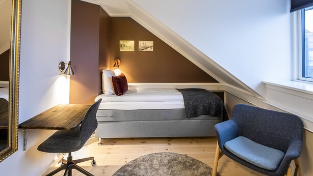 A compact bedroom with a bed, a desk, and a chair. - Hotel Sidesporet (Holbaek)