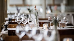 A dining table set with wine glasses, a candle, and a vase with dried flowers. - Hotel Sidesporet (Holbaek)