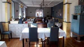 Un restaurant amb una zona central de menjador que inclou taules i caires, un mur amb un disseny i un penjallum.