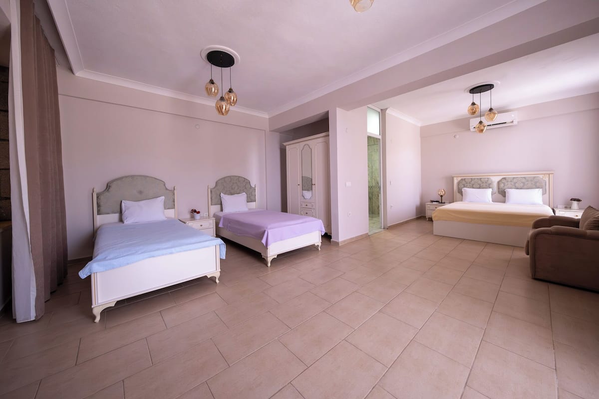 A spacious bedroom with two beds, a sofa, and a walk-in closet.