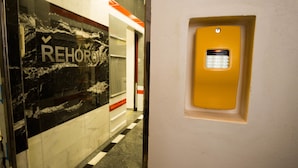 A hallway with a marble wall and a yellow intercom box. - METRO Apartment (Prague)