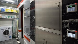 A compact hotel room with a washing machine, a dryer, and a Jablotron security keypad. - METRO Apartment (Prague)