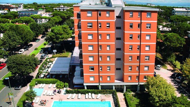 Een meerlaags hotel met een zwembad, terras en een restaurant.