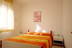 A bedroom with a bed, a nightstand, a lamp, and a framed picture on the wall.