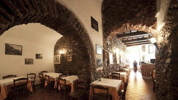 Un restaurante con arcos de piedra, mesas y sillas de madera.