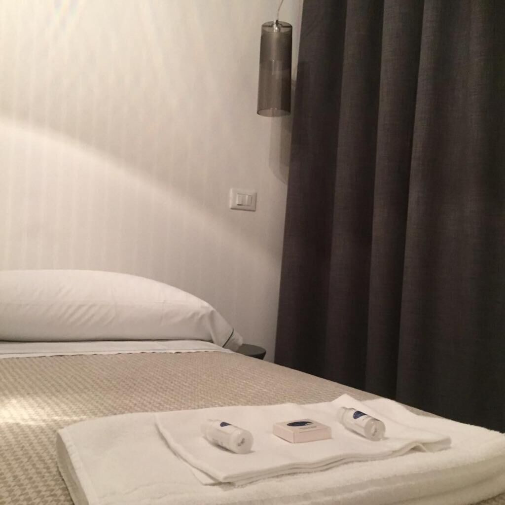 Une chambre d’hôtel avec un lit, une table de chevet, une lampe et une serviette sur laquelle sont posés des articles de toilette.