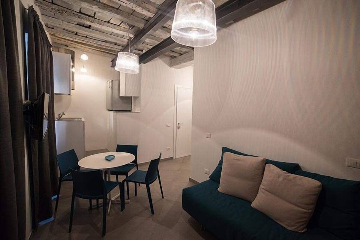 A modern kitchen with a dining area, a sofa, and pendant lights.