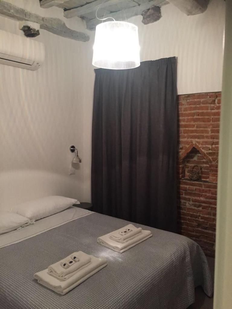 A room with a bed, a brick fireplace, and a hanging light fixture.