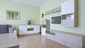 A modern living room with a sofa, TV, and built-in entertainment unit. - Italianway - Casasco 79 (Centro Valle Intelvi)