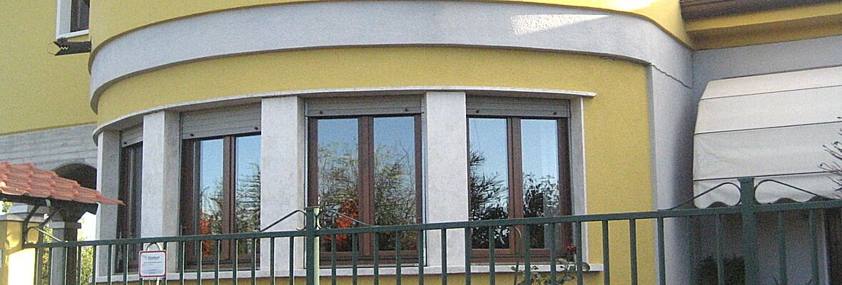 Un immeuble d’angle à la façade incurvée, doté de grandes fenêtres et d’un balcon.