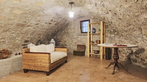 A rustic room with a stone wall, a wicker sofa, a wooden table with wine glasses, and a window. - Italianway - Santa Maria 37 (Nesso)