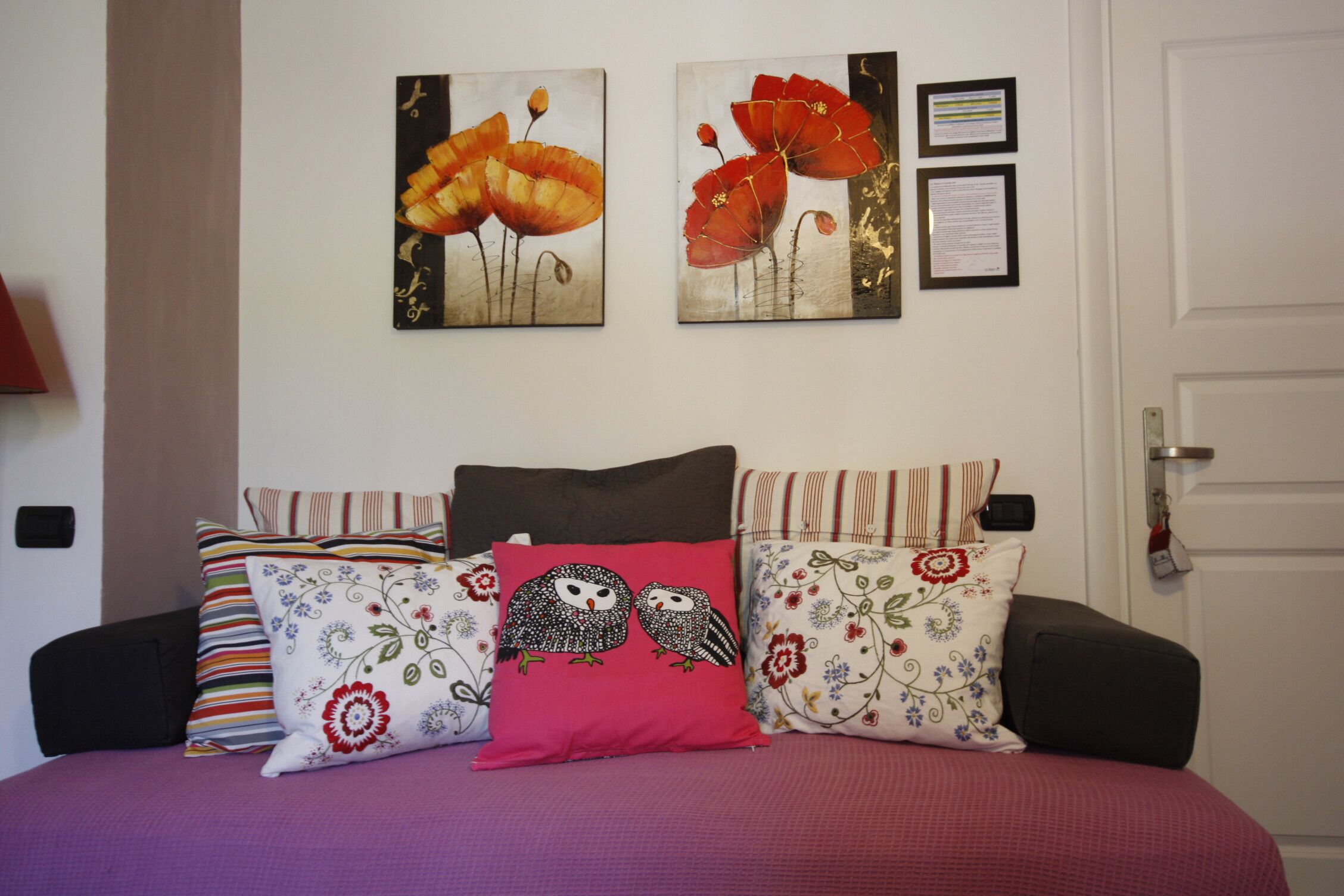 Una cama con múltiples almohadas y dos cuadros en la pared.