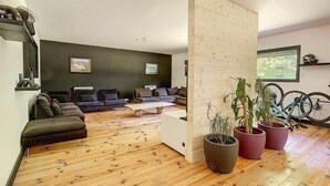 A modern living room with a wooden floor, dark sofas, a white coffee table, and potted plants. - Villa Maya Uma (Vendays-Montalivet)