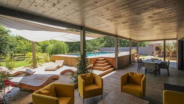 A covered outdoor area with wooden flooring, yellow chairs, a pool, and a staircase leading to a deck. - Villa Maya Uma (Vendays-Montalivet)