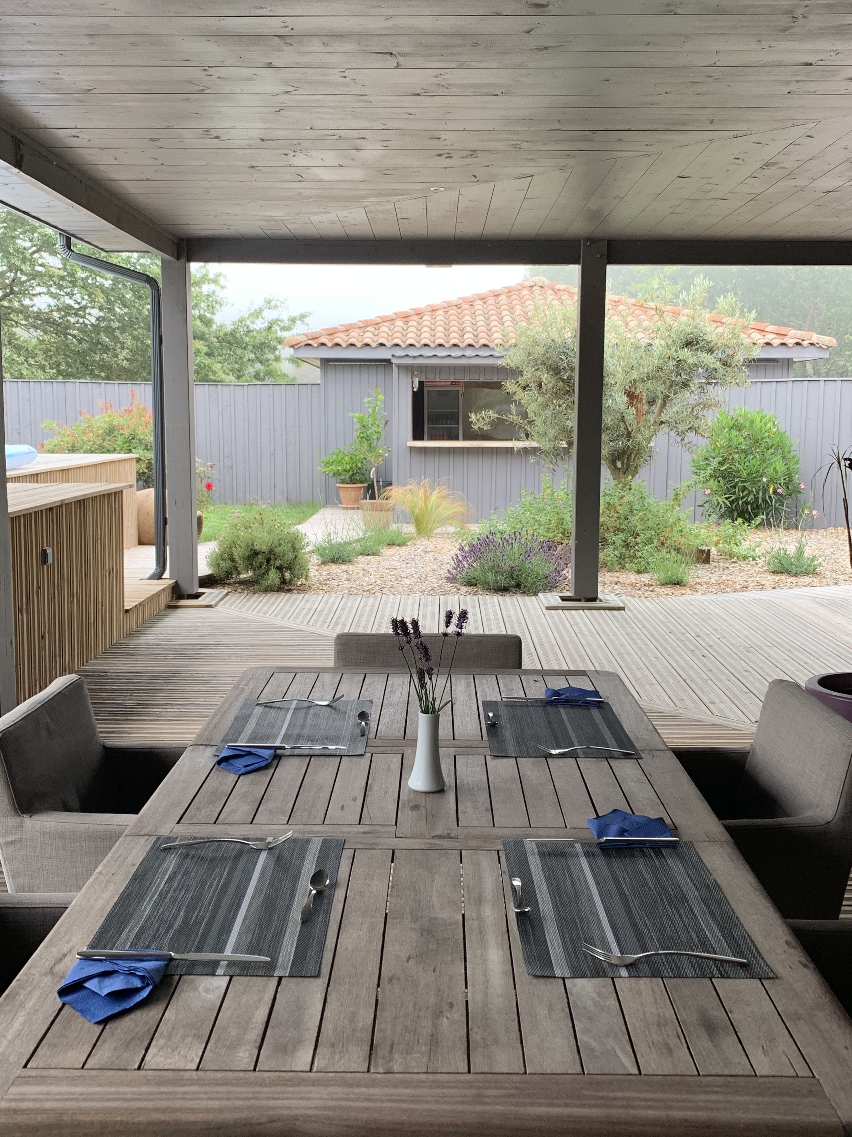An outdoor patio with a wooden table set for dining, surrounded by cushioned seating.