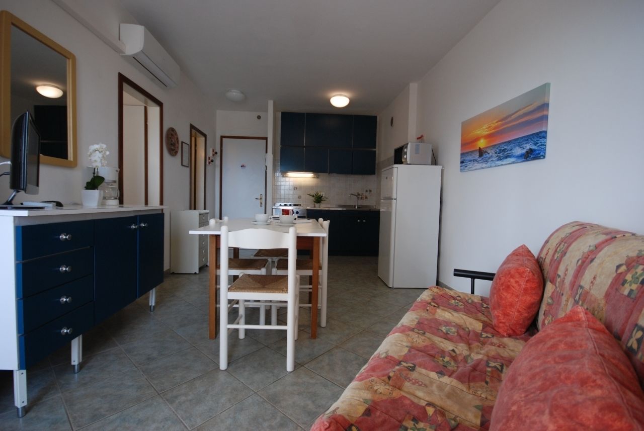 Een compacte leefruimte met een kitchenette, een eethoek en een bank.